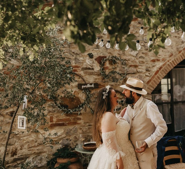 Bride and groom standing in front of olive bouquet guestbook wall