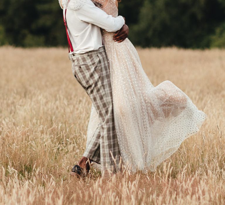 Groom lifts bride in fields at Longton Wood