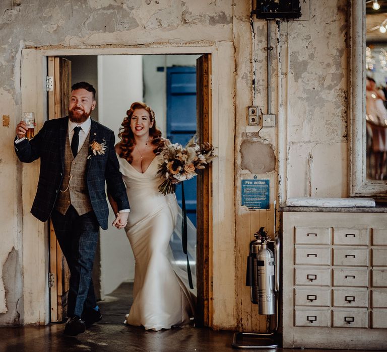 Bride with vintage wedding hair and groom entering their micro wedding reception 