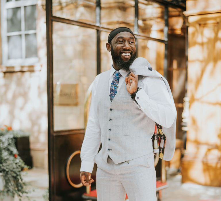 Black groom in a three piece sand suit with blue paisley tie 