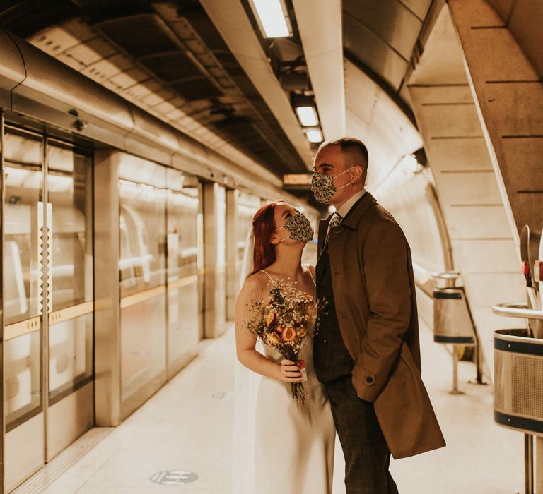 Couple at London underground on their wedding day during covid wearing face masks 