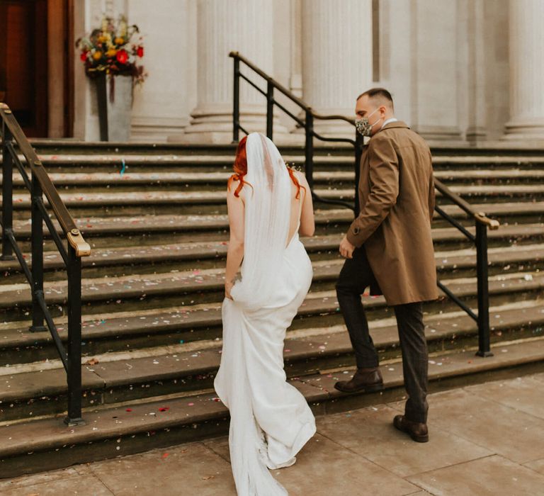 Bride and groom walking up steps to their wedding venue for their London elopement 