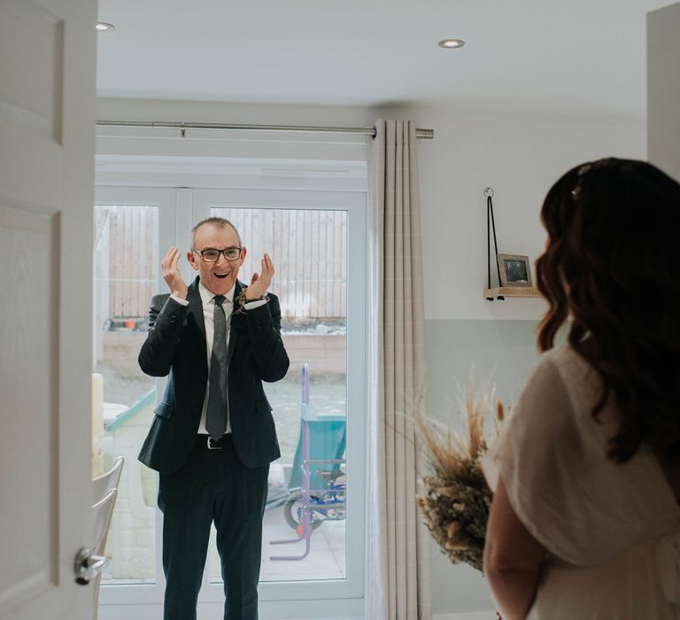 Happy father-of-the-bride in black suit sees bride for the first time