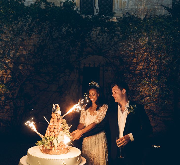 Couple cut croquembouche outdoors while flare sparklers set off