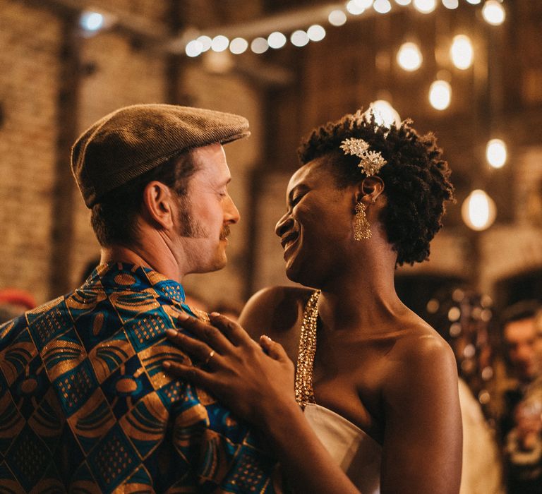 West African bride with short hair dancing with her groom in traditional outfits 