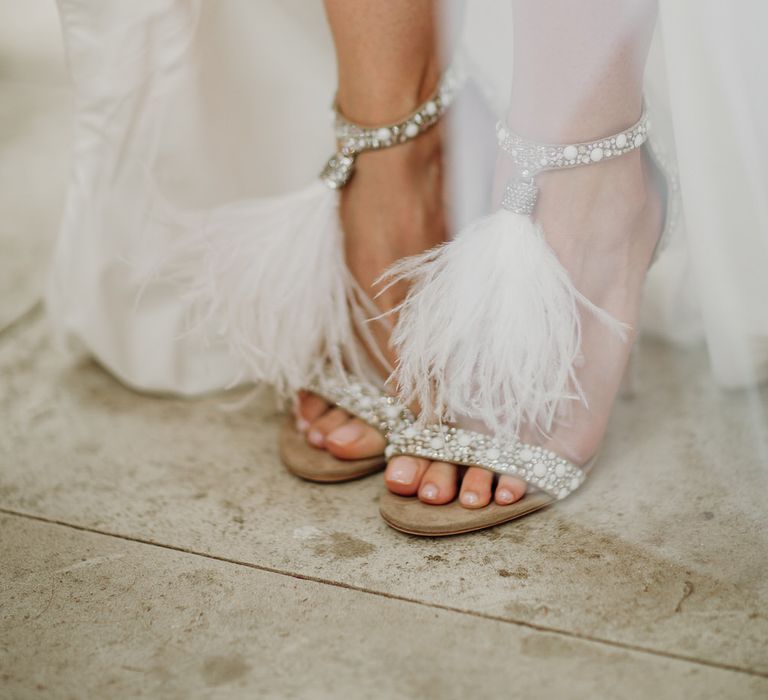 Close up of bride's silver Jimmy Choo heeled sandals with white feather details 