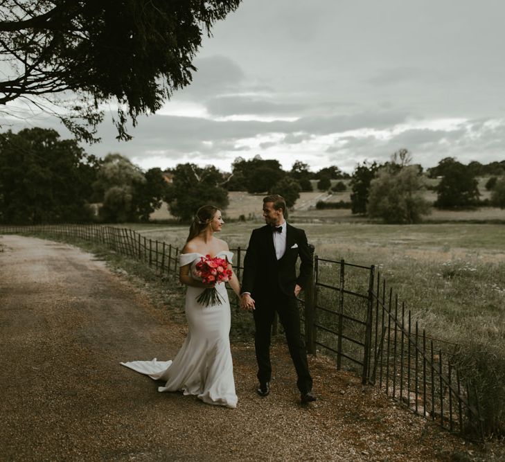 Bride & groom walk together whilst holding hands