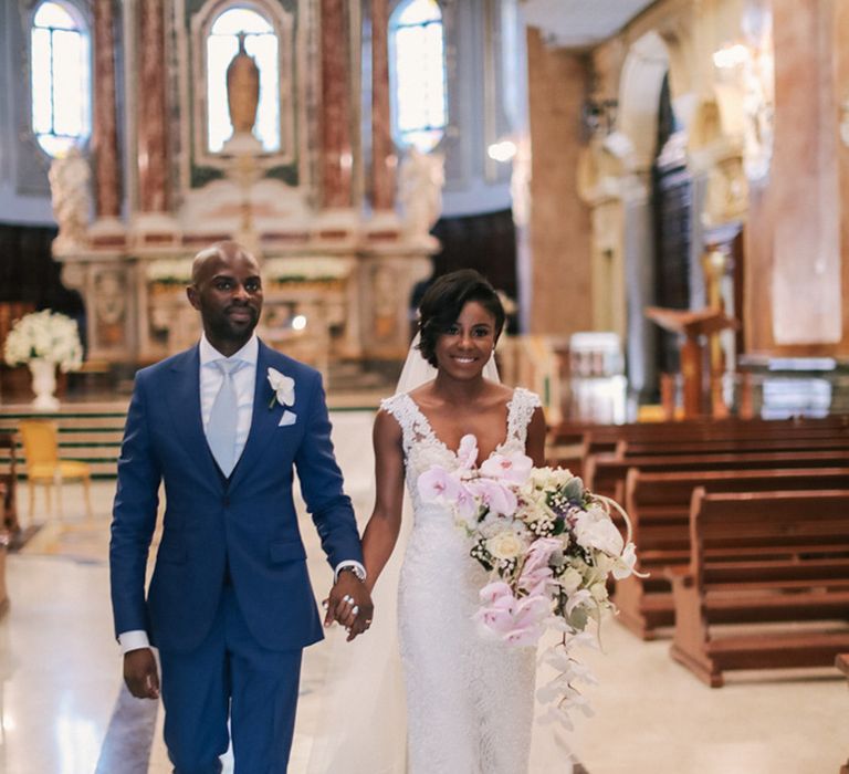 A Black bride and groom exit their church wedding ceremony. She carried a bouquet of orchids. 