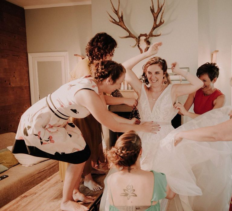 The bride surrounded by her five bridesmaids who are all helping her get ready at once