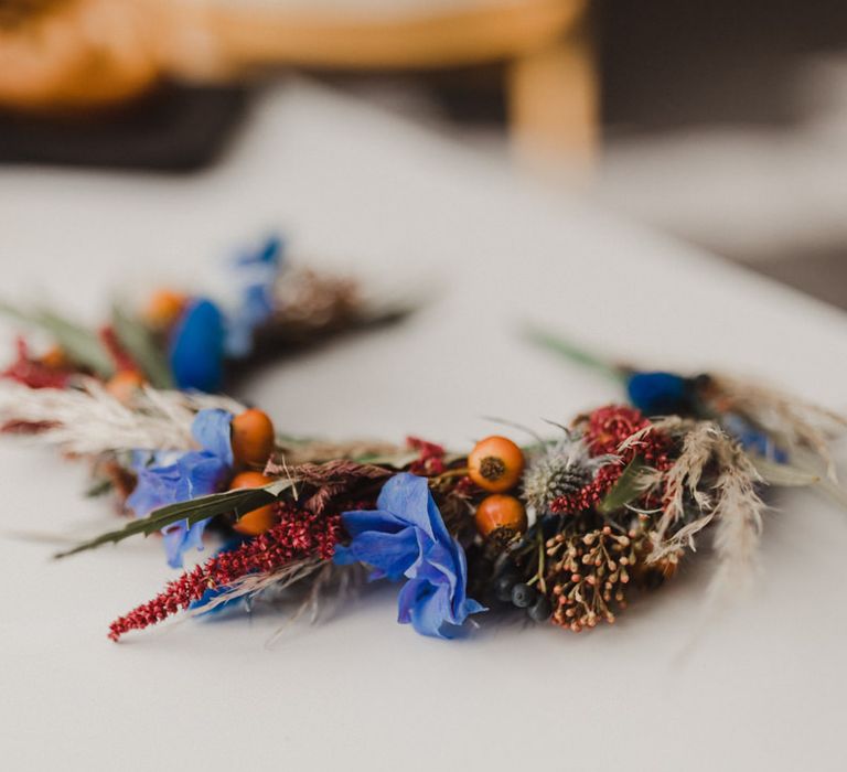 Red and blue flower crown with thistles and berries