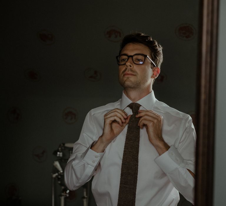 Groom adjusts his tie on the morning of wedding