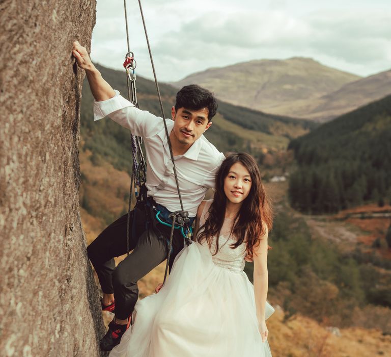 Couple smile for the camera during rock climbing engagement session 