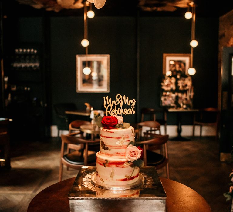 Wedding cake with accent gold and red colours and Mr & Mrs cake topper in gold