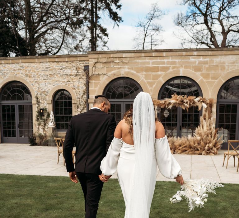 Bride in a fitted wedding dress with off the shoulder detail, puddle train and polka dot veil 