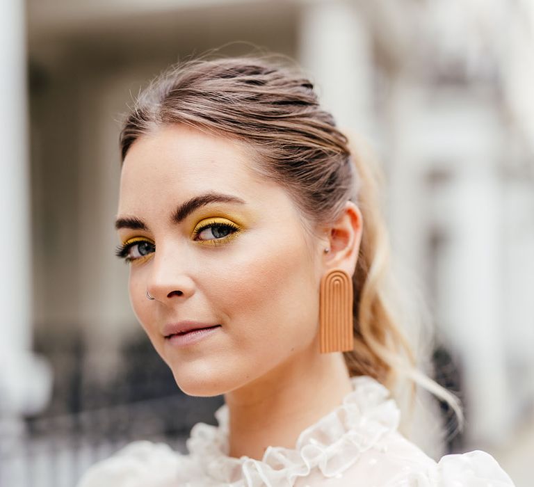 Yellow wedding makeup and retro earrings for stylish micro bride 