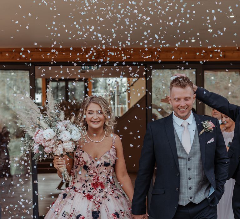 Bride & groom walk through confetti after their wedding ceremony