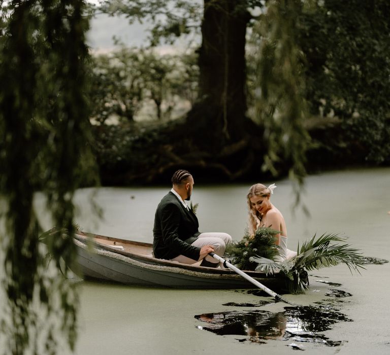 Bride and groom in a rowboat on a green algae covered lake for tropical wedding theme