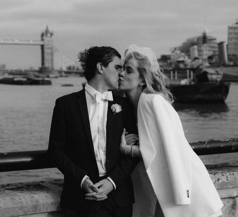 Bride and groom kissing at London wedding overlooking River Thames 