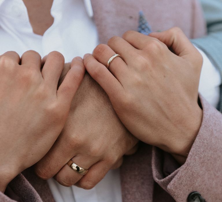 Grooms embrace outdoors whilst wearing pastel suits