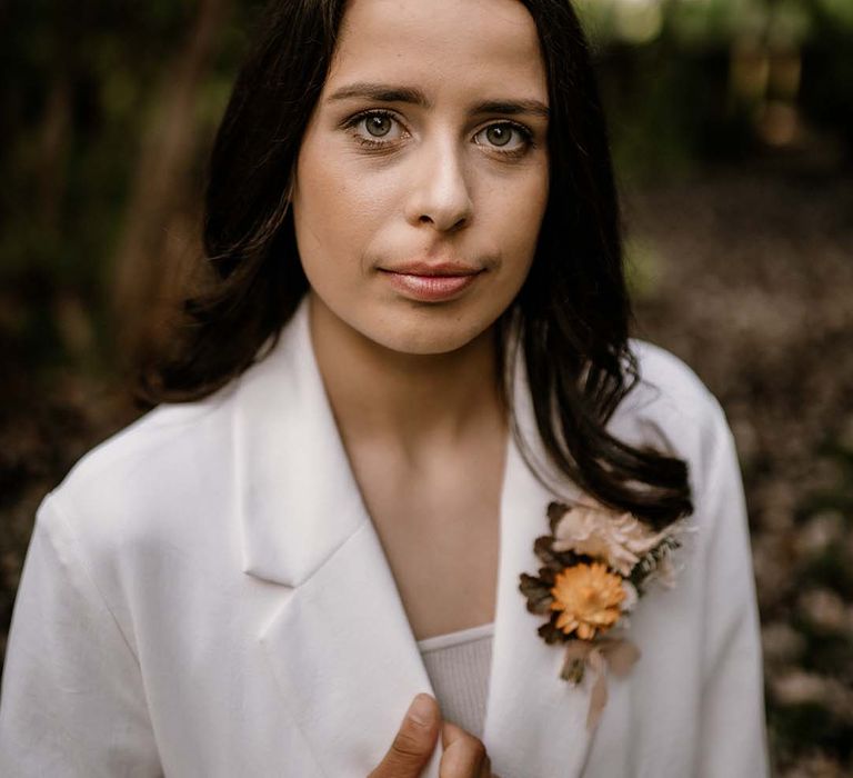 Beautiful bride with long hair in a white blazer and yellow buttonhole flower 