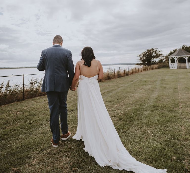 Bride and groom walking along the coast at their Osea Island wedding 