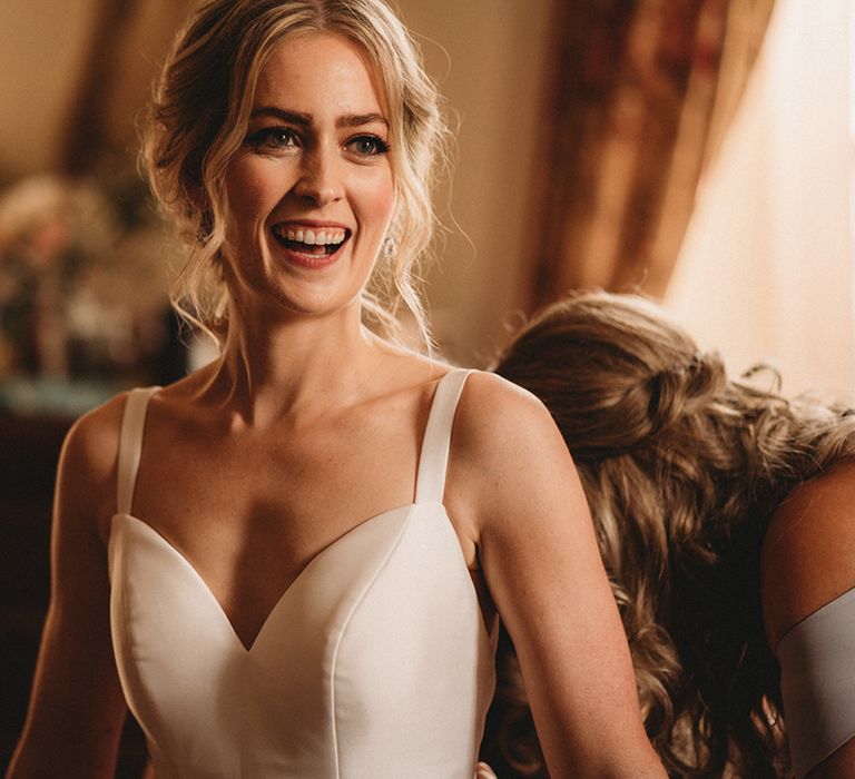 Beautiful bride in a Stella York wedding dress with straps on the wedding morning with tousled pinned up wedding hair 