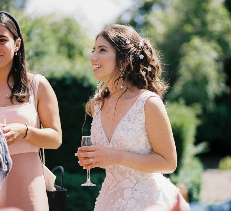 Bride laughs with wedding guests on her wedding day as she wears her dark hair in tight curls