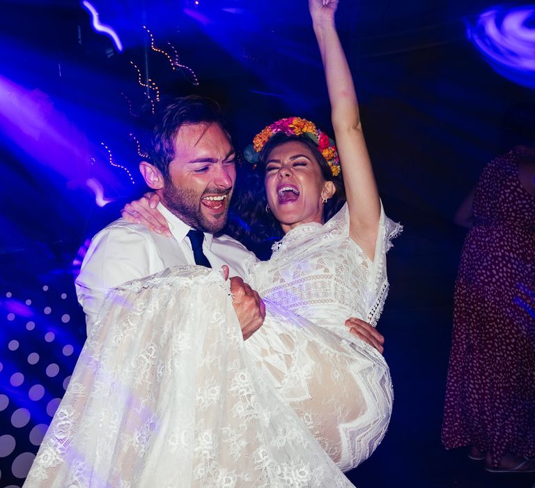 Bride in lace Grace Loves Lace wedding dress and flower crown and groom in white shirt dance during evening wedding reception at The Bridal Barn in Claverley