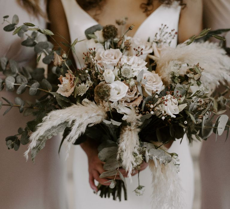 Bride holds her floral bouquet filled with white flowers