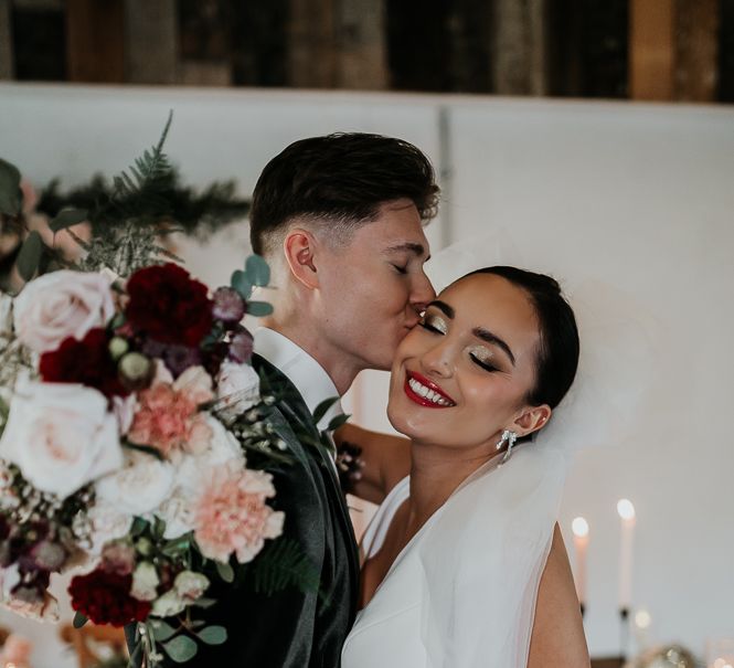 Groom kisses his brides cheek 