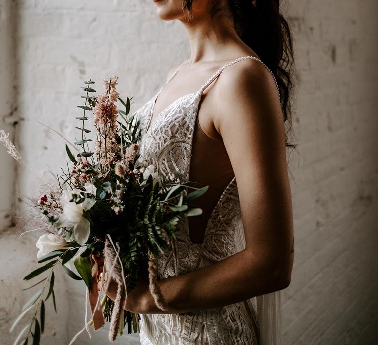 Bride in a lace wedding dress with thin straps in a neutral and red dried flower crown 