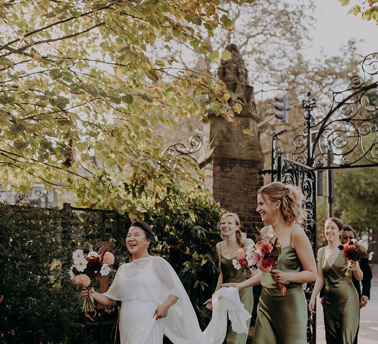 Bride walks along with her bridesmaids who hold her wedding cape | Irene Yap Photography