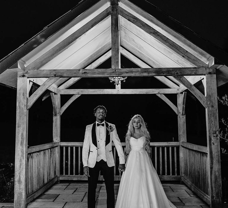 Bride in strapless wedding dress holds hands with groom in tuxedo