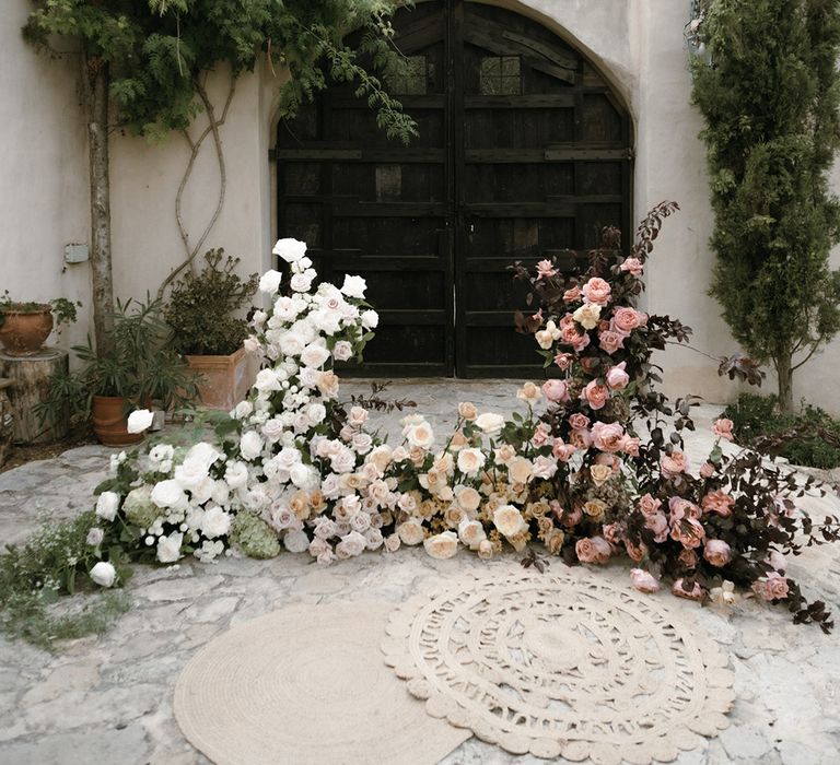 White, pink and orange roses and greenery for floral display altar style with beige rugs