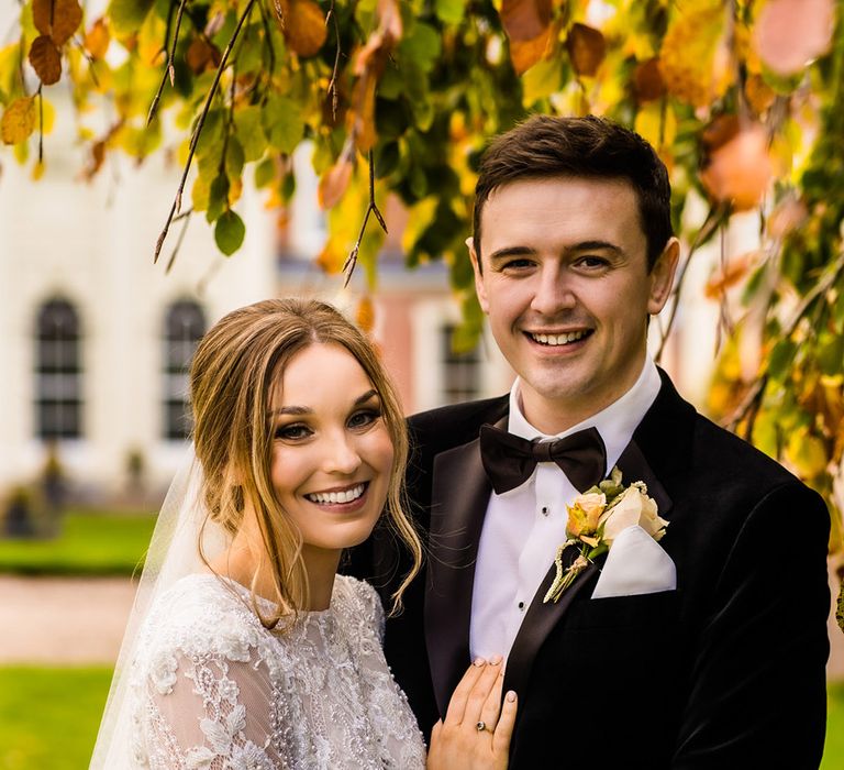 Bride and groom hold each other and smile at the camera