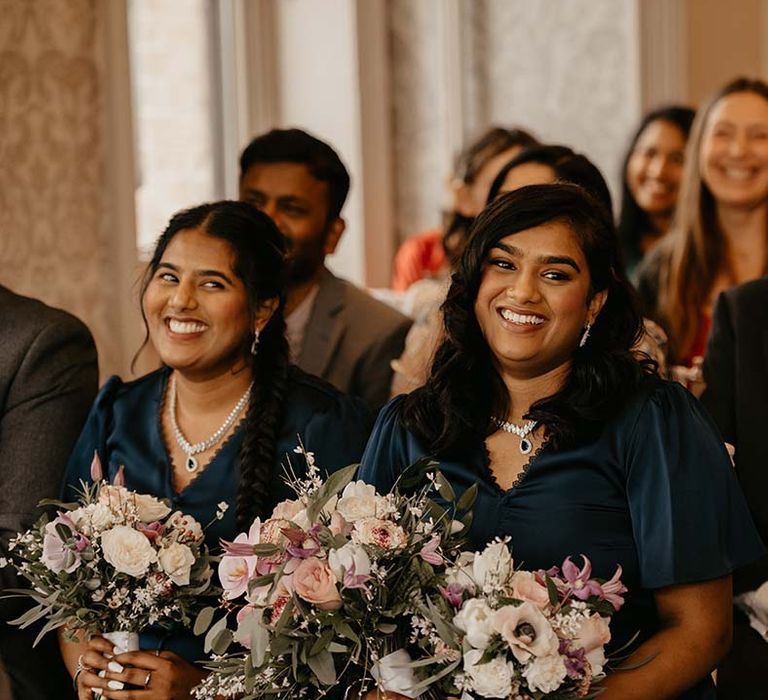 Bridesmaids in dark green bridesmaid dresses with button details and mixed floral bouquets