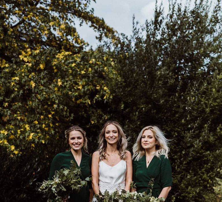 Bride with bridesmaids in forest green wrap dresses with natural green foliage bouquets