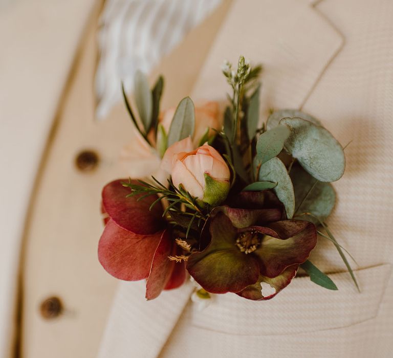 delicate groom buttonhole flower pinned to a beige suit 