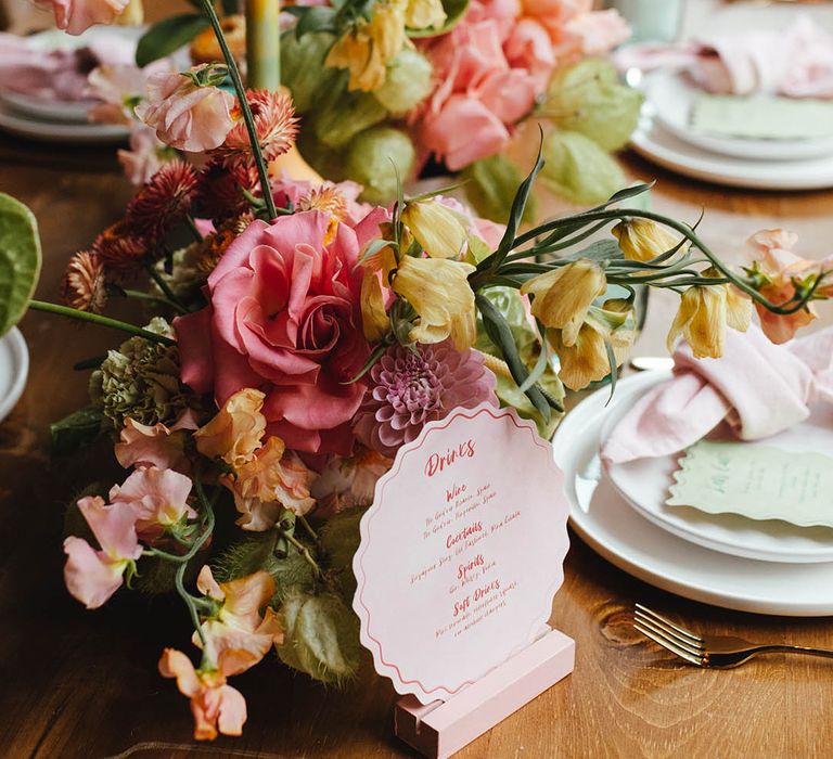 yellow, green, pink flower arrangement and drinks on the day wedding stationery table sign 