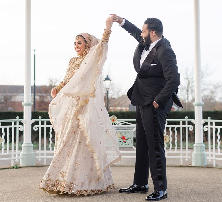 Groom who wears black tie spins his bride around as she wears traditional saree which blows in the wind