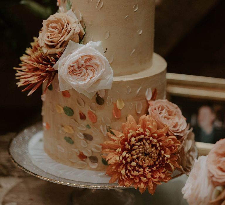 Two tier wedding cake with flowers and painted icing design