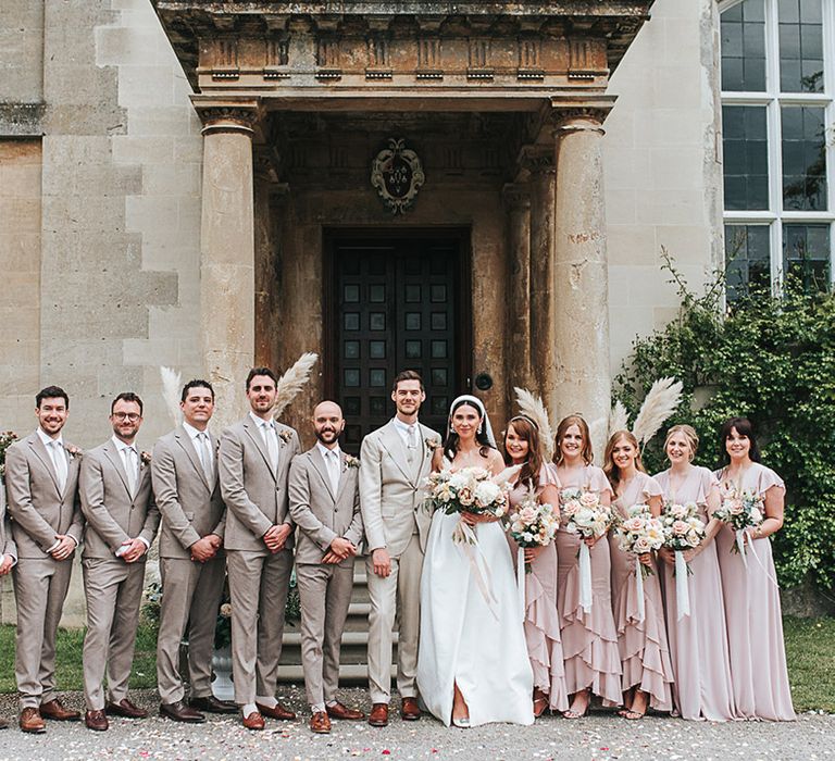 Wedding party with bridesmaids in pink dresses and grooms in neutral suits for contemporary and boho style wedding 