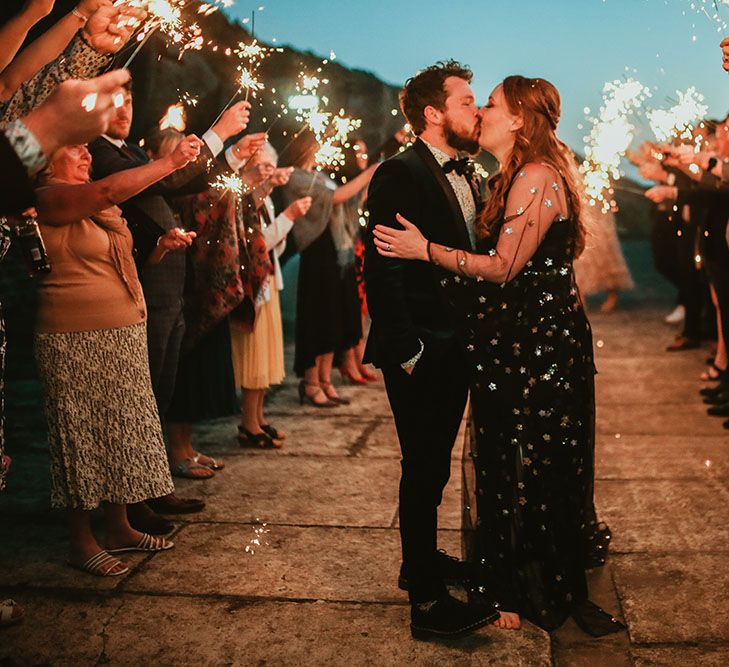 Bride & groom kiss during sparkler exit outdoors on their wedding day