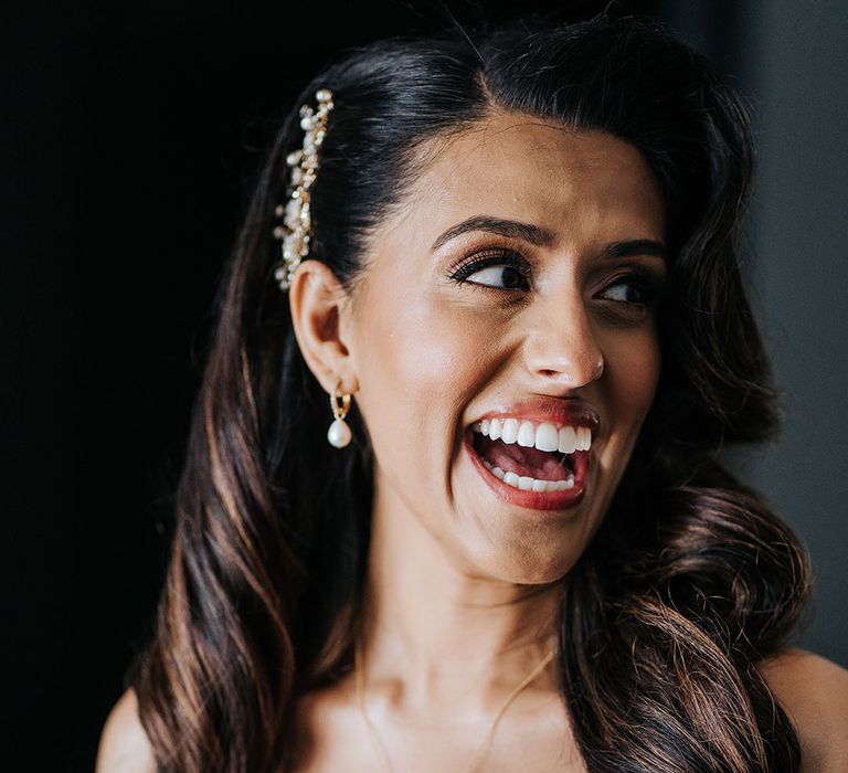 Indian bride wears natural makeup and pearl drop gold earrings with embellished hair accessory 