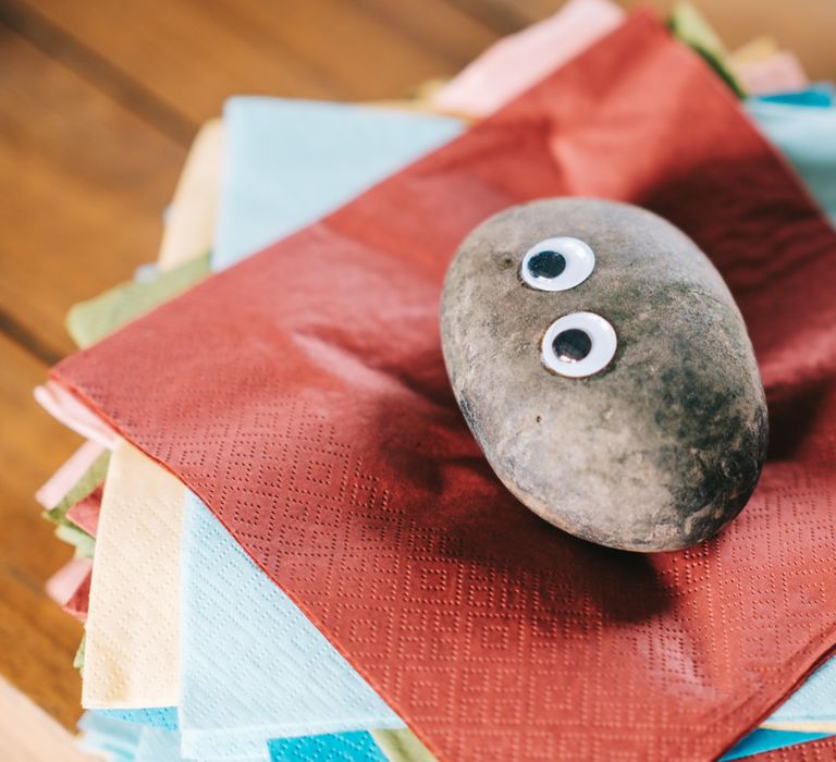 Stone holders with painted eyes on top of colourful napkins