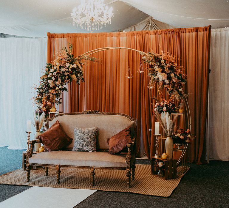 Autumnal styled floral archway with sofa beneath for bride & groom 