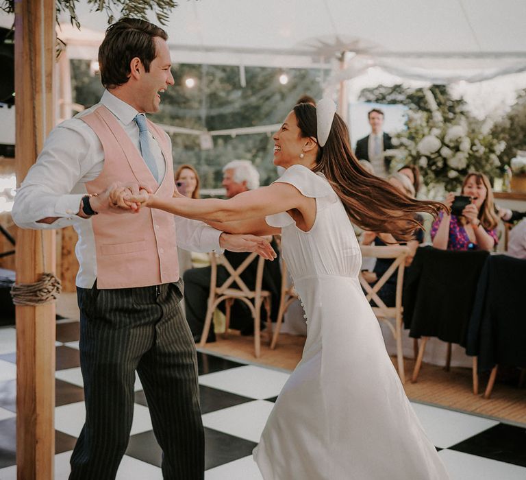 Bride in a colourful pastel pink and blue waistcoat with bride in a satin Ghost wedding dress having their first dance 