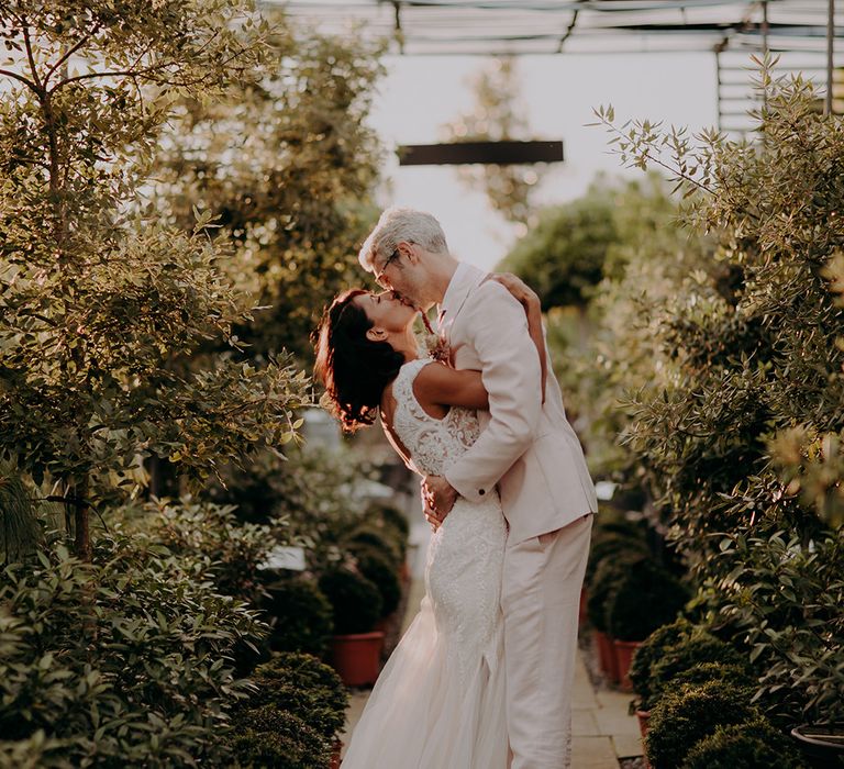 Bride and Groom embrace and kiss whilst surrounded by trees