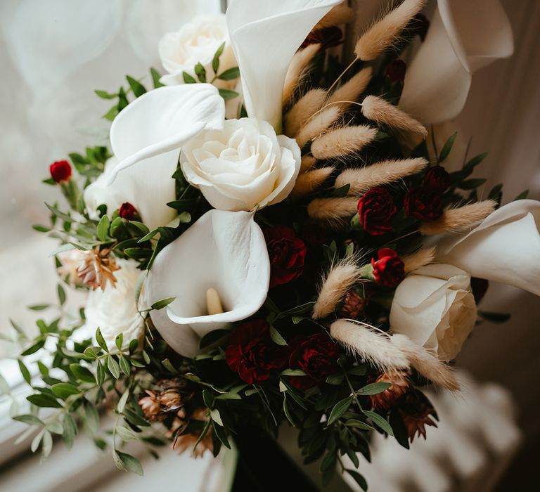 White orchid bridal bouquet complete with roses, bunny tails and green foliage 