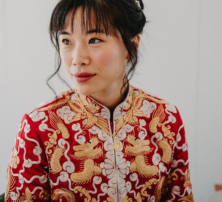 East Asian Bride wears traditional red Chinese wedding dress with gold embellishment 